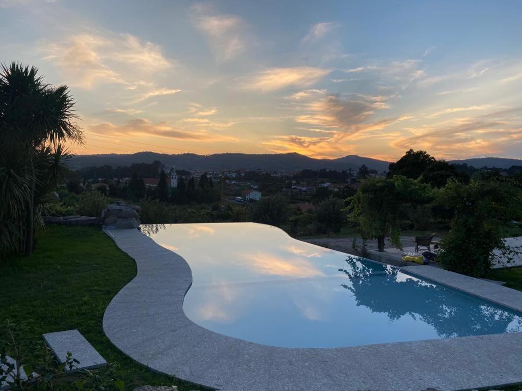 a swimming pool with a sunset in the background at Hotel Quinta da Tulha in Guimarães