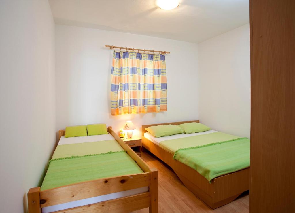 two beds in a small room with a window at Apartments Fani in Brela