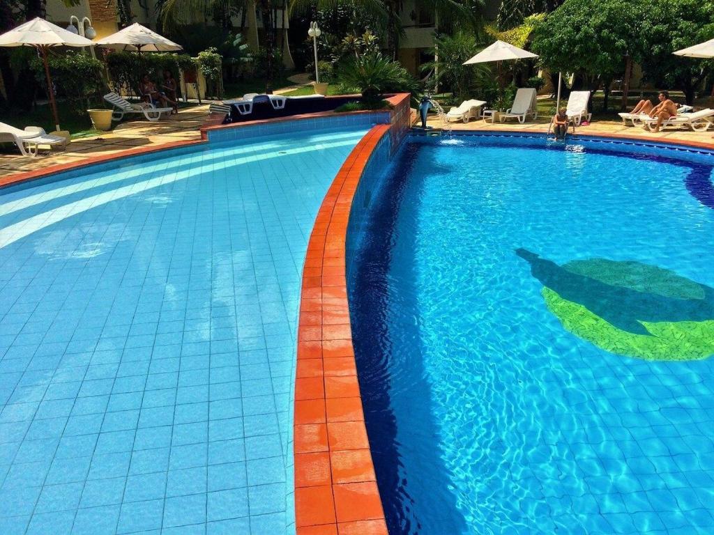 a large blue swimming pool with a red curb at Solar de Pipa Duplex Flat in Pipa