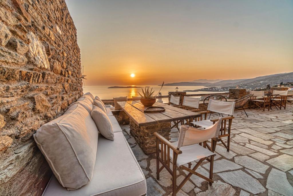 a patio with a couch and a table with a sunset at IRIDA Villa - Sea & Sunset Flats by Explore Andros in Batsi
