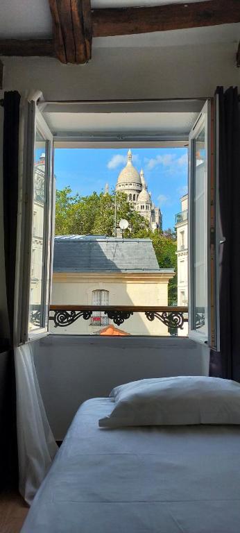 a bedroom with a window with a view of a building at Le Village Montmartre in Paris