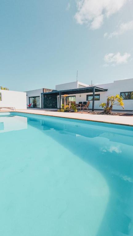 a view of a swimming pool with a house in the background at Villa Wind Wave 28A Heated & Shared Pool in Lajares