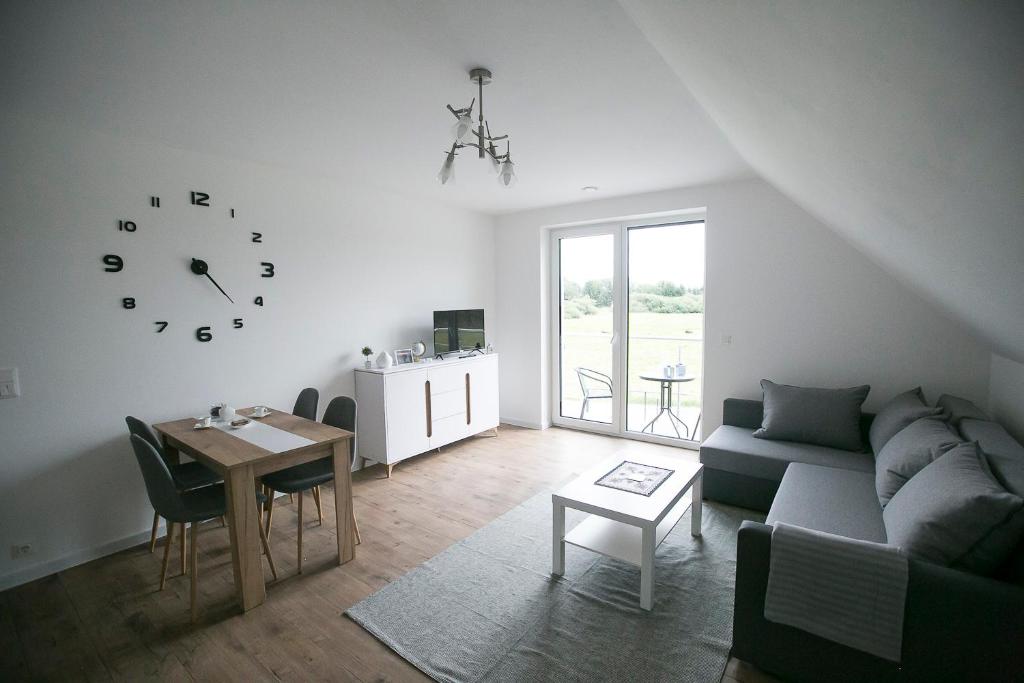 ein Wohnzimmer mit einem Sofa, einem Tisch und einer Uhr in der Unterkunft Apartamenty Perła Orawy in Zubrzyca Dolna