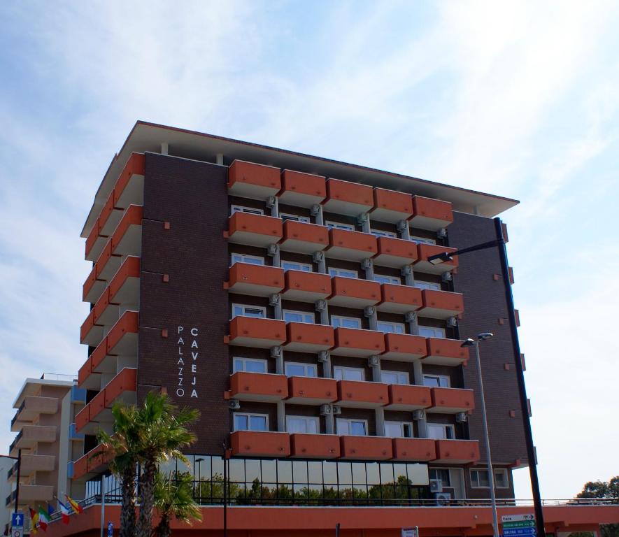 a large building with red balconies on it at Hotel Palazzo Caveja in Rimini