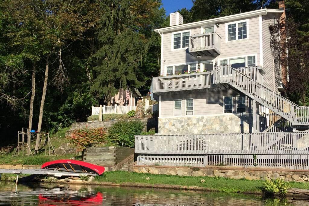 una casa blanca con un bote rojo en el agua en Large family house on the lake, en Hewitt