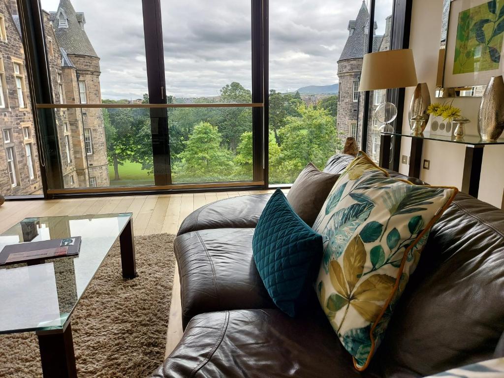 a leather couch in a living room with a large window at Quartermile Luxury Landing Apartment in Edinburgh