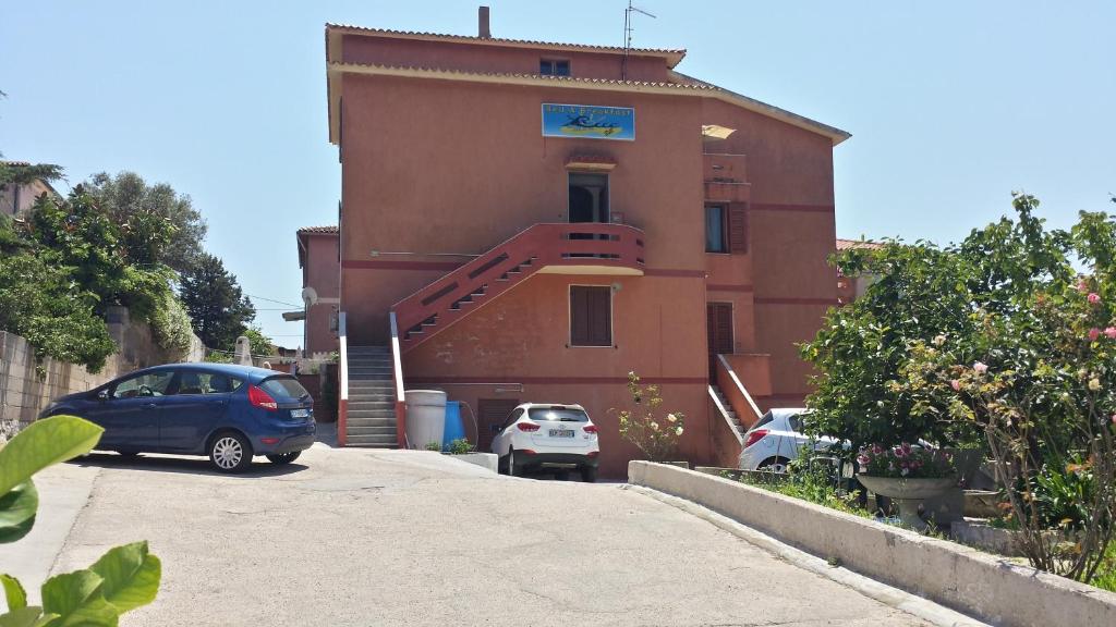 a building with two cars parked in front of it at Guest House Tra Rocce E Mare in La Maddalena