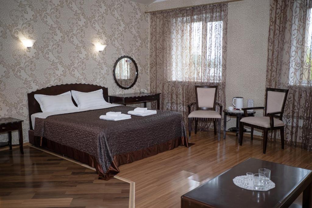 ナホトカにあるBoomerang Hotelのベッド、テーブル、椅子が備わるホテルルームです。