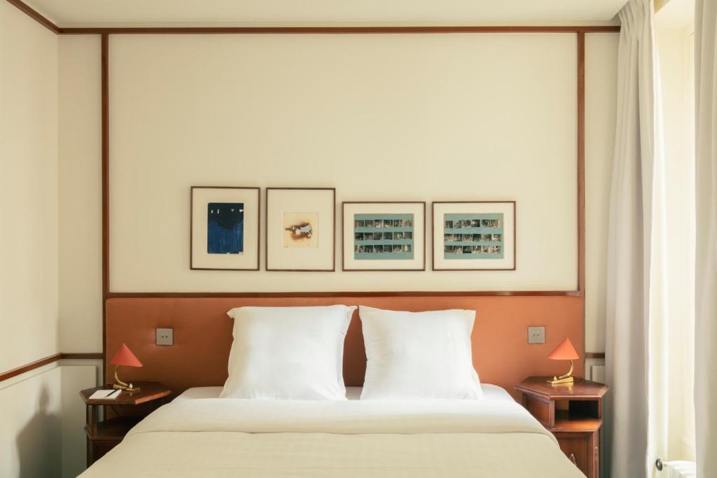 een slaapkamer met een groot bed met vier foto's aan de muur bij Pied A Terre - Saint Honoré in Parijs