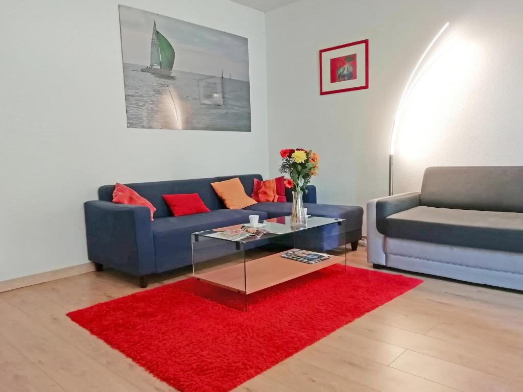 a living room with two blue couches and a red rug at L'écrin du quercy in Figeac