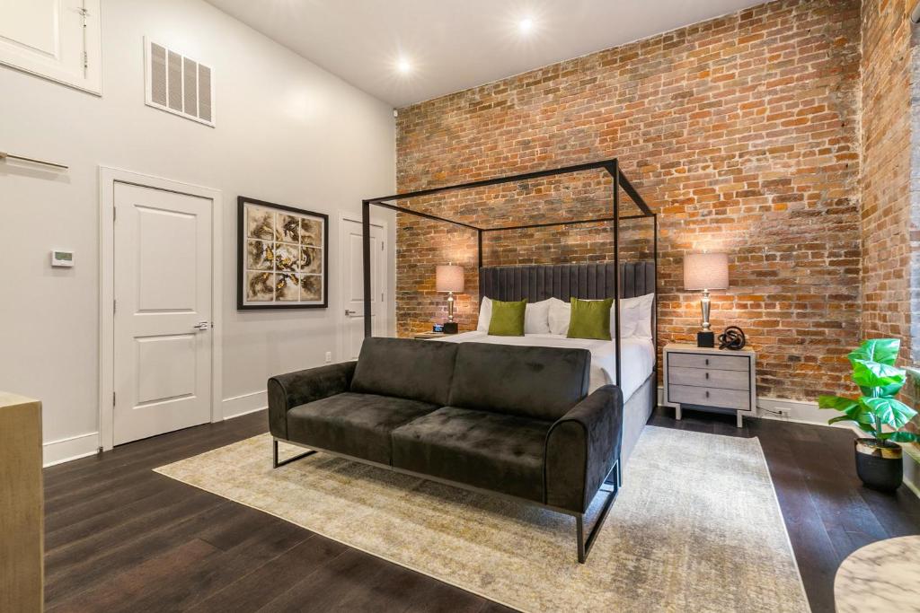 a bedroom with a bed and a couch in front of a brick wall at The Sazerac in New Orleans