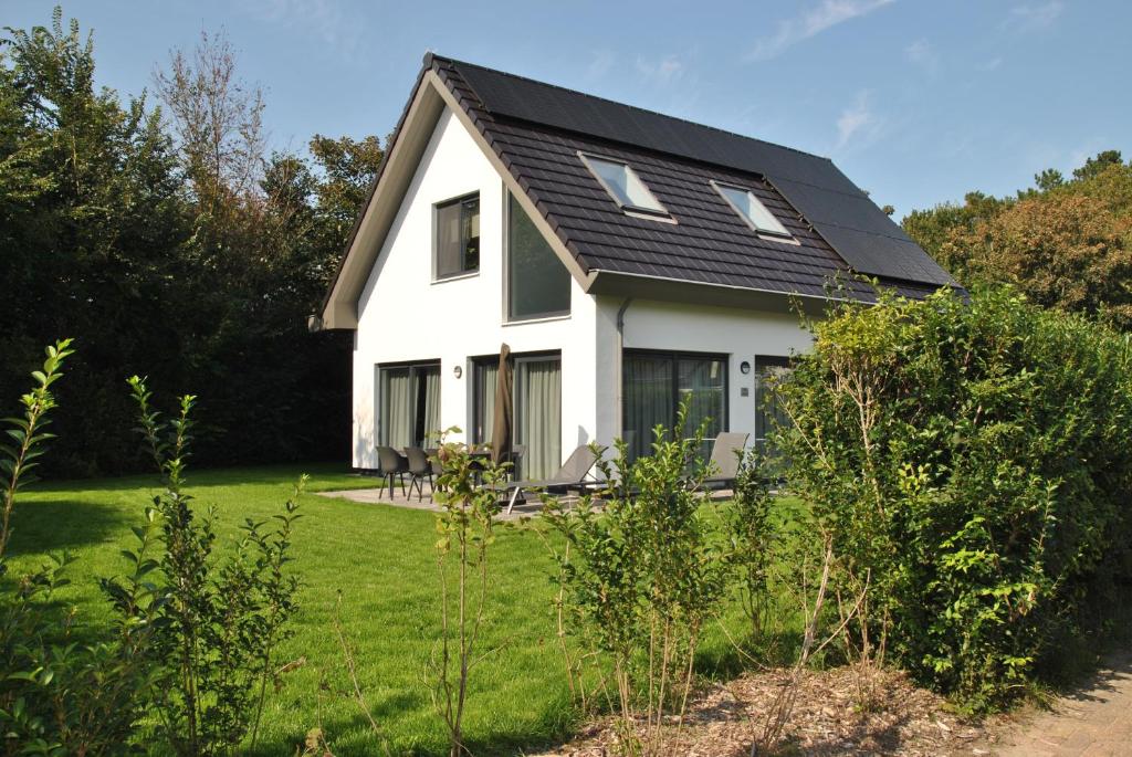 una casa blanca con techo negro en Vakantiewoning De Bleekersvallei, en De Koog