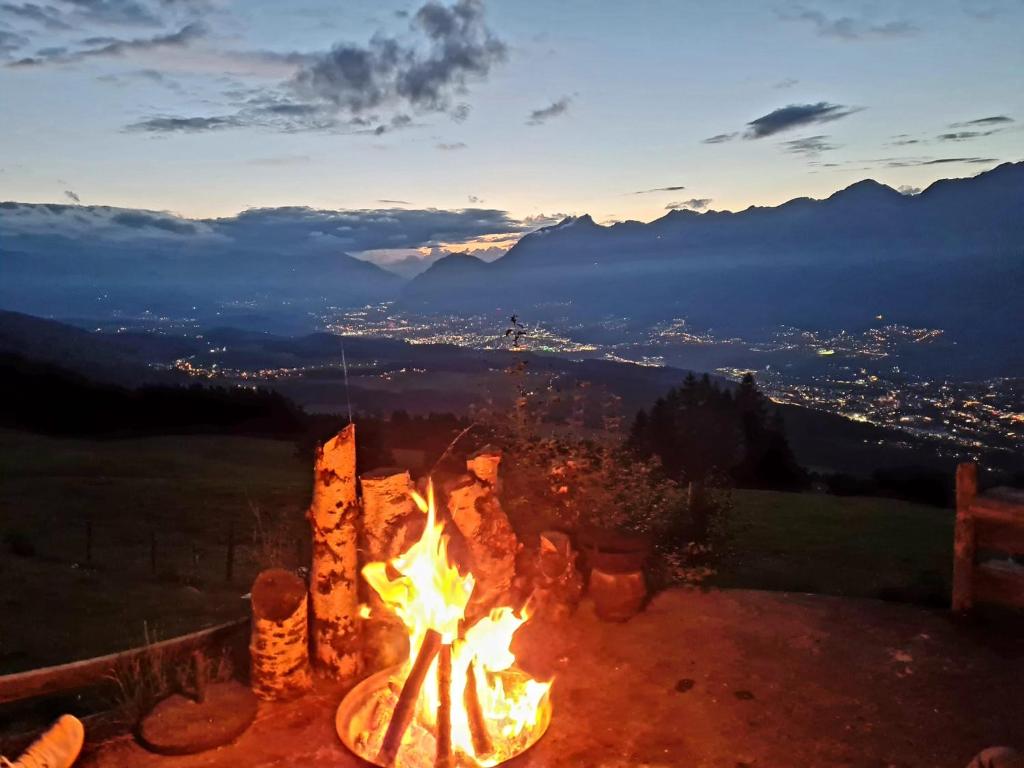 a fire pit with a view of a city at night at Walters Hütte in Tulfes