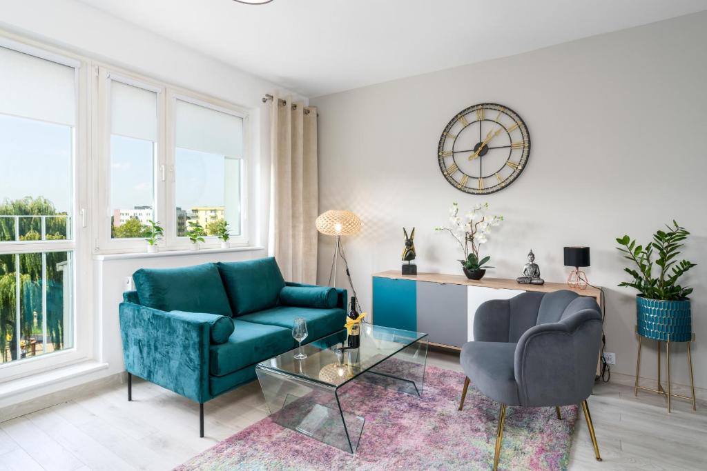 a living room with a couch and two chairs and a clock at Apartments Poznań Keplera by Renters in Poznań