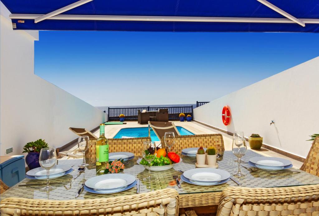 a dining room with a table and a swimming pool at Brisa Marina in Puerto Calero