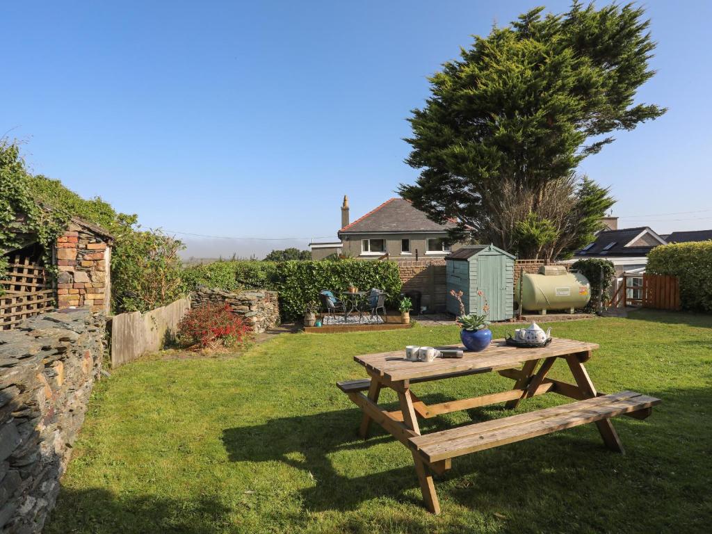 a wooden picnic table in the grass in a yard at Hazel Bank Cottage in Amlwch