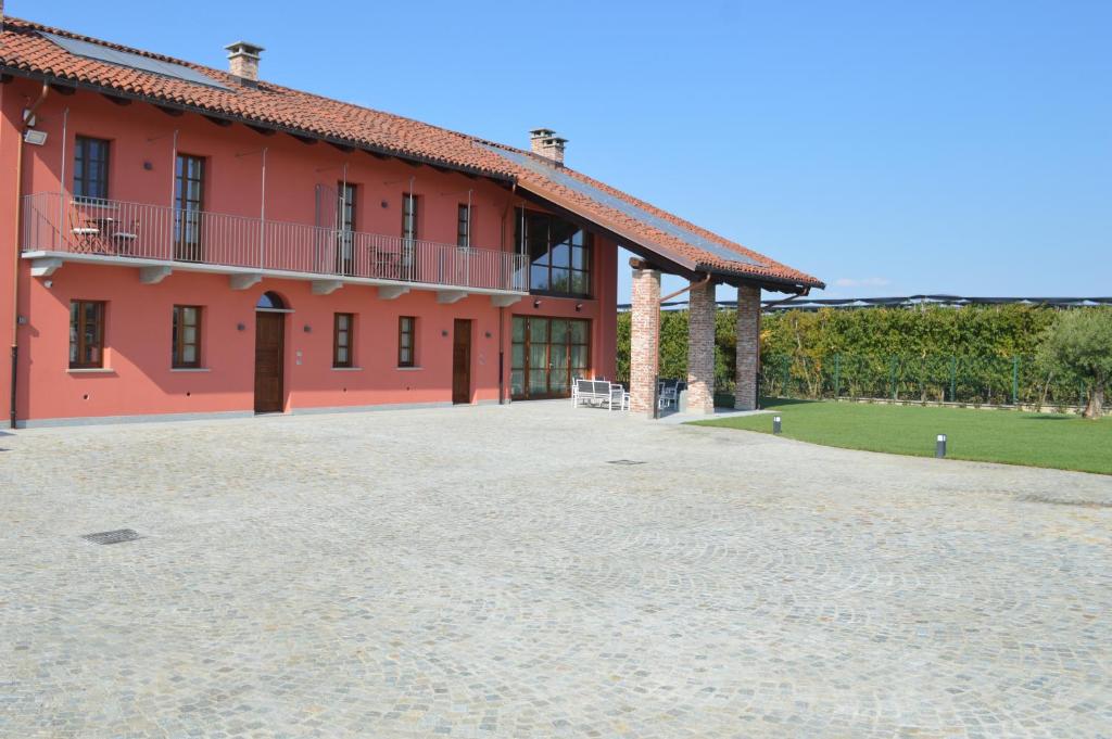 a red building with a large driveway in front of it at B&B La Luce Verde in Saluzzo