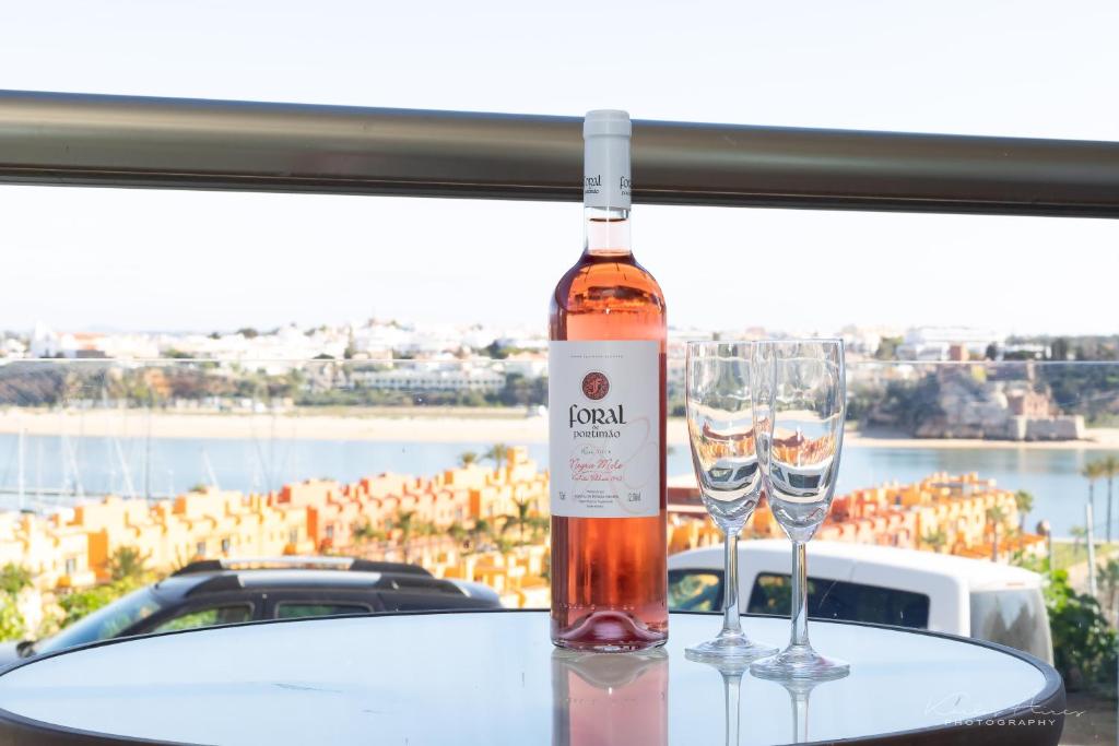 uma garrafa de vinho sentada numa mesa com dois copos em Pé na Areia praia da Rocha em Portimão