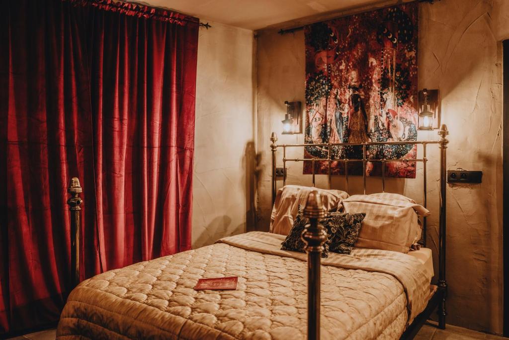 1 dormitorio con 1 cama y cortinas rojas en Le Fantôme de Berthe logement-attraction insolite, en La-Roche-en-Ardenne