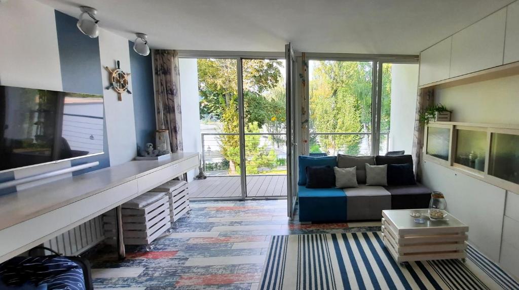 salon z niebieską kanapą i dużym oknem w obiekcie Apartament Lazurowy 53 z tarasem i SPA w mieście Gródek Nad Dunajcem