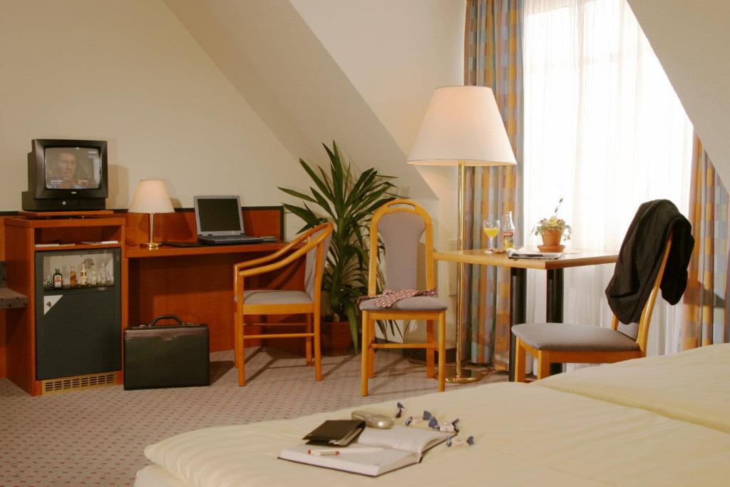 um quarto de hotel com uma cama, uma mesa e cadeiras em Andersen Hotel Schwedt em Schwedt