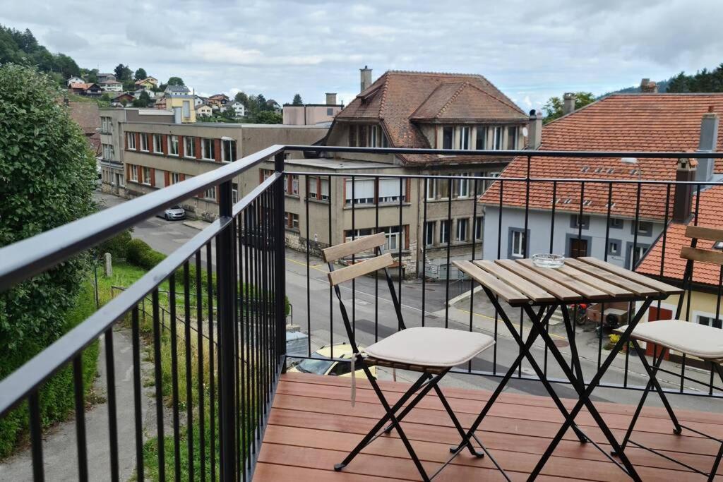 a balcony with a table and chairs and a view of a city at Petit bijou de Sainte-Croix in Sainte-Croix