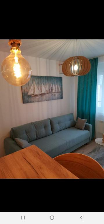 a living room with a blue couch and two lights at PREMIUM APARTMAN JAGODINA in Jagodina
