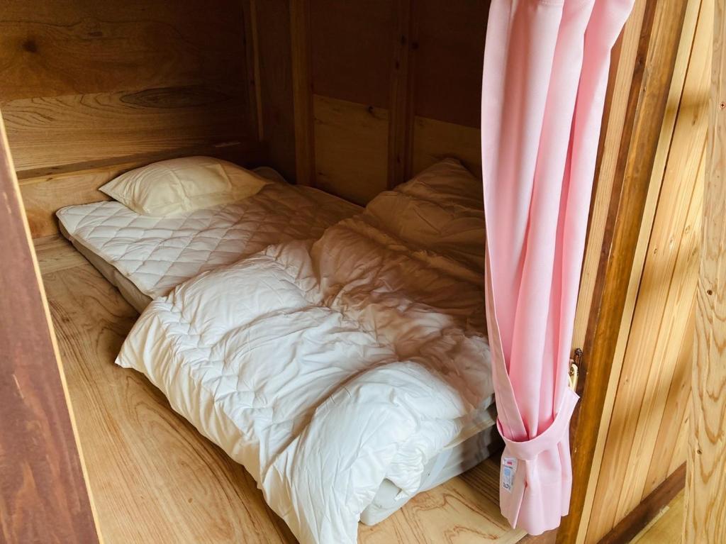 a small bed in a room with a pink curtain at Challenge kyoten YOKANA - Vacation STAY 63968v in Noma