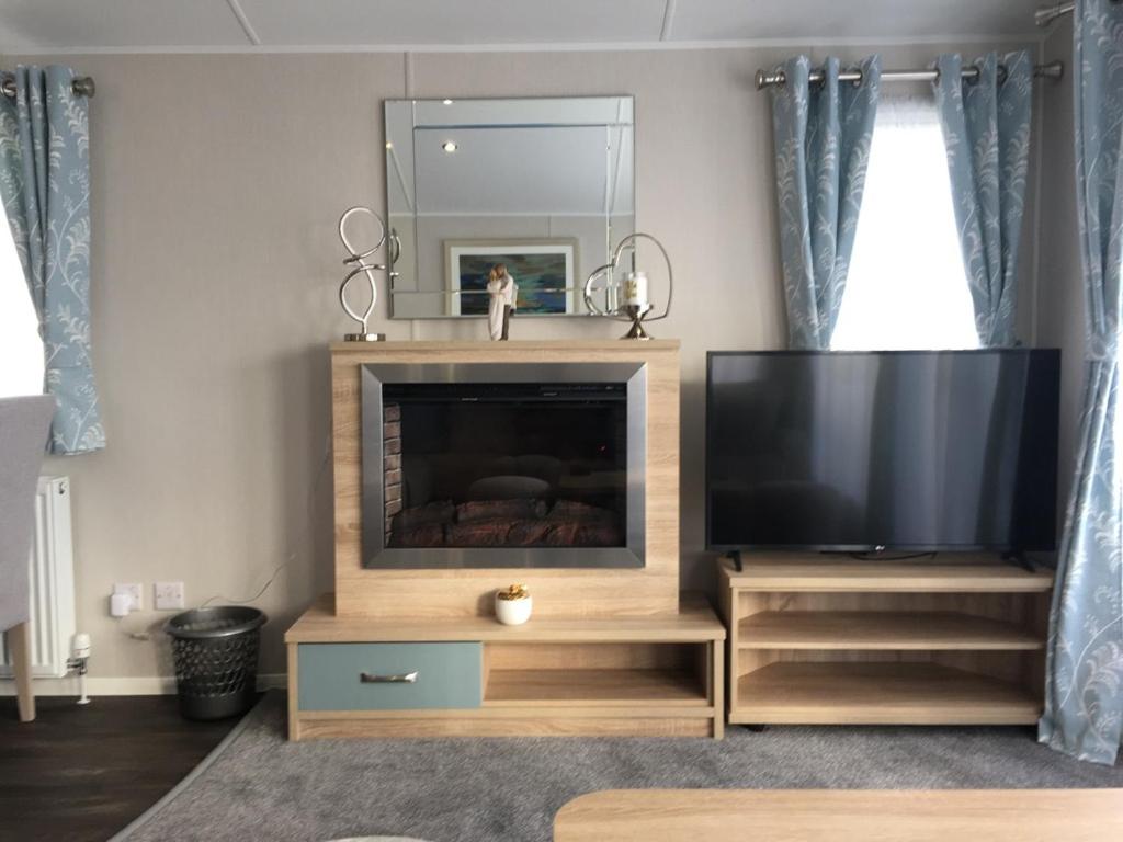 uma sala de estar com televisão e espelho em 6 Swan View Haven, Littlesea em Weymouth