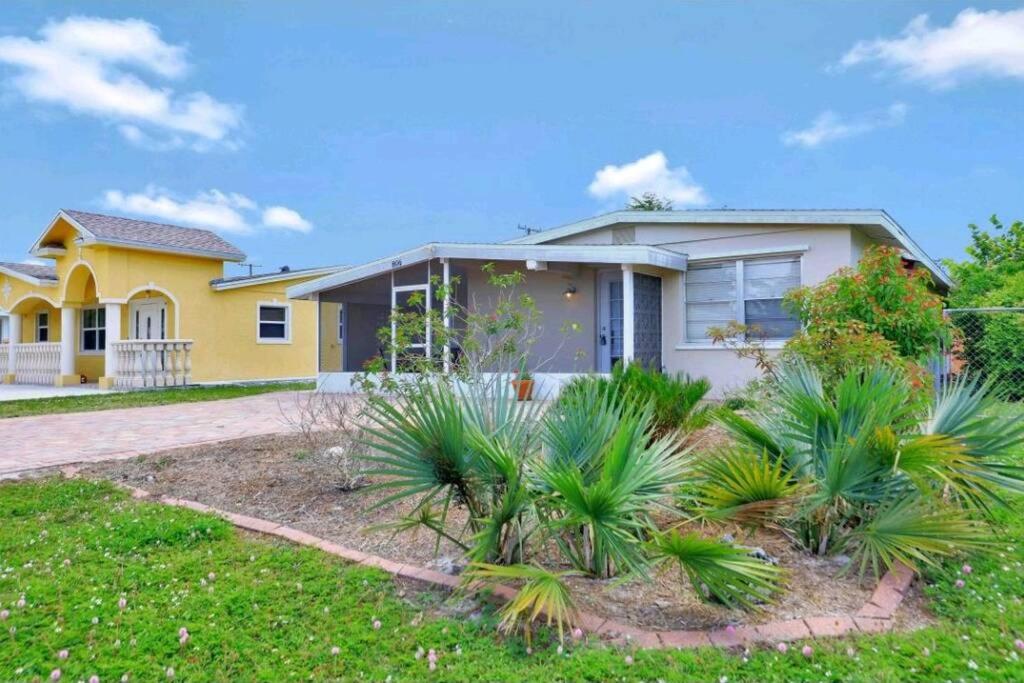 a yellow house with palm trees in front of it at Comfy 3 bedroom with parking & close to everything in Naples