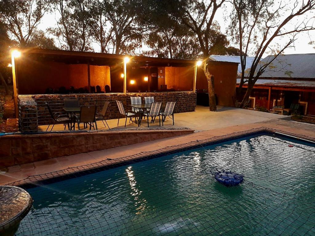 a swimming pool with a table and chairs at night at Rocky Hollow Lodge in Pretoria