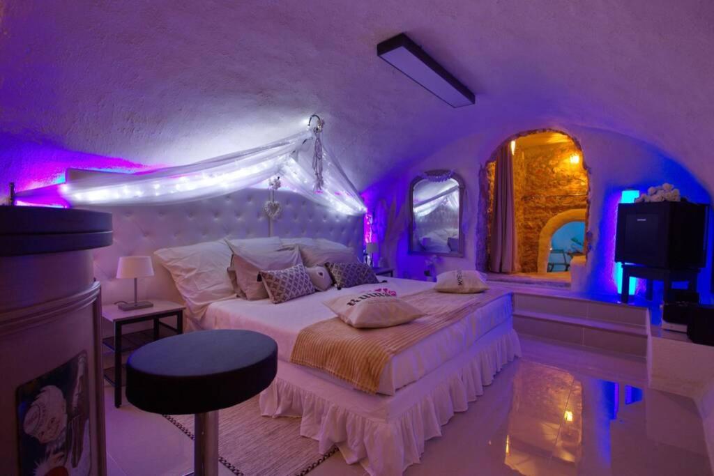 um quarto com uma cama com iluminação roxa em Les Secrets d'Alcôve, nuits Romantiques avec SPA em Aix-en-Provence