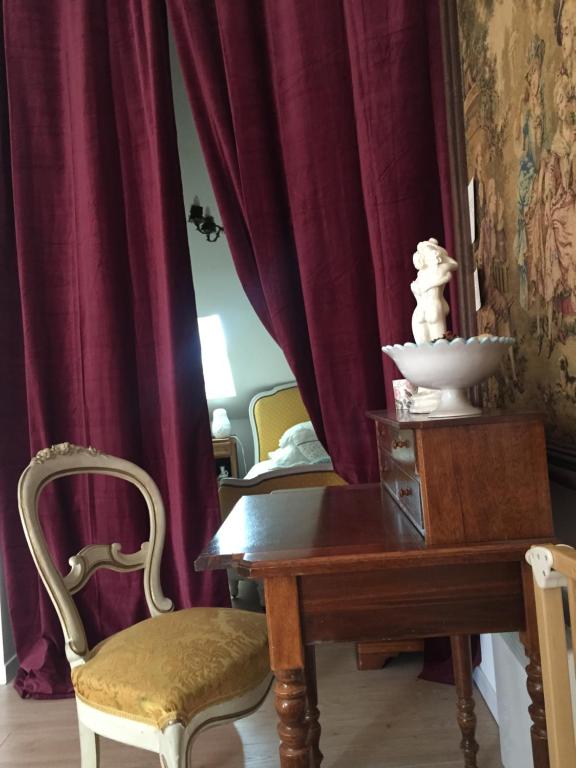 a dining room with a table and chairs and red curtains at La Romanée in Sallaumines