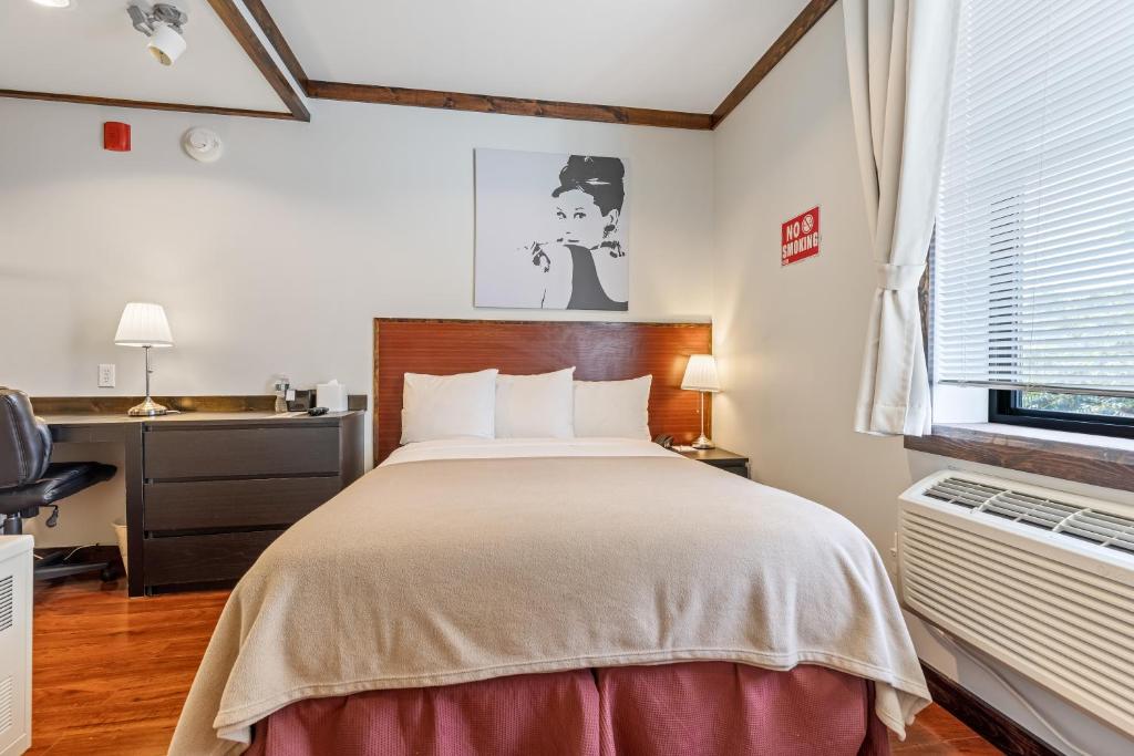 ein Schlafzimmer mit einem Bett, einem Schreibtisch und einem Fenster in der Unterkunft LIC Hotel in Queens