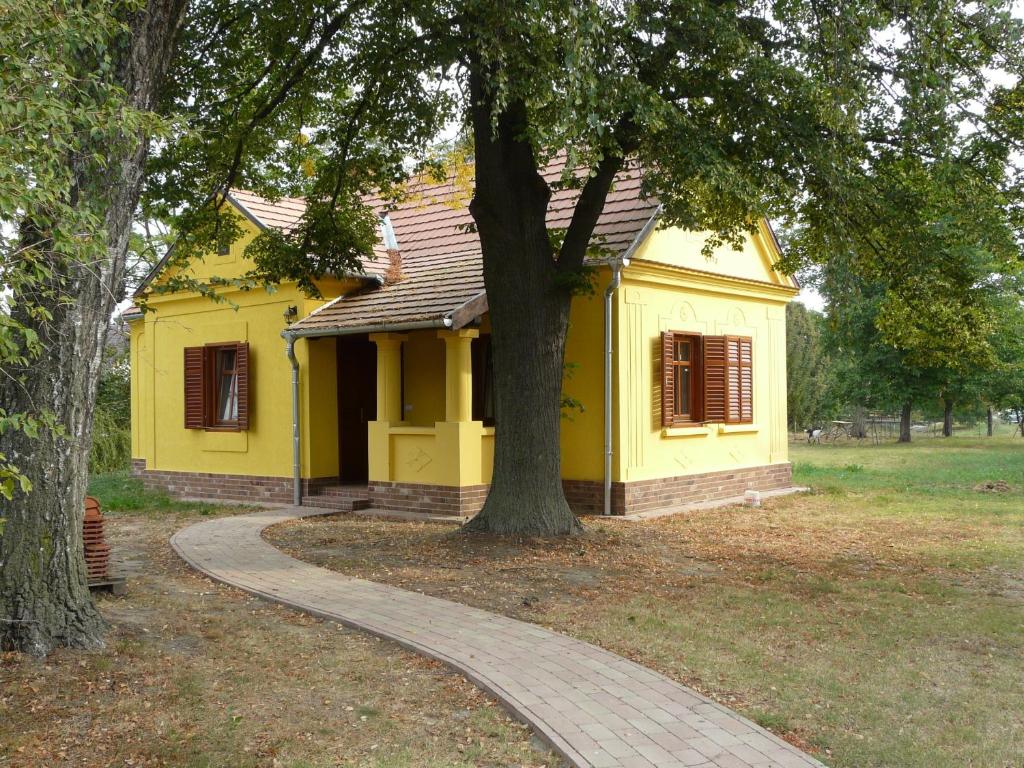 uma casa amarela com uma árvore em frente em Márfi vendégház em Magyarszerdahely