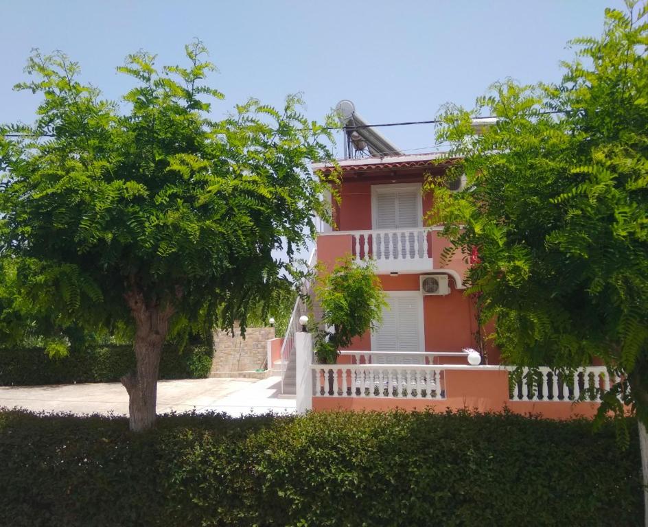 una casa rossa con una recinzione bianca e un albero di Panagiotis Studios a Laganas