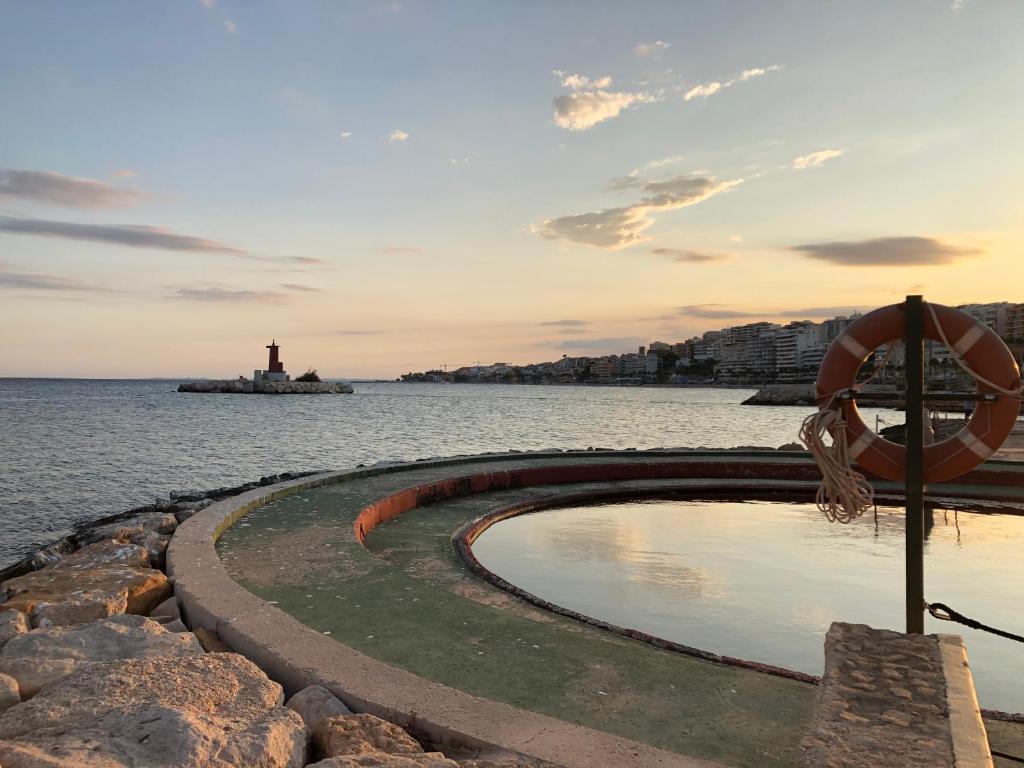 a swimming pool next to the water with a lighthouse at Apartamento Plaza in Villajoyosa