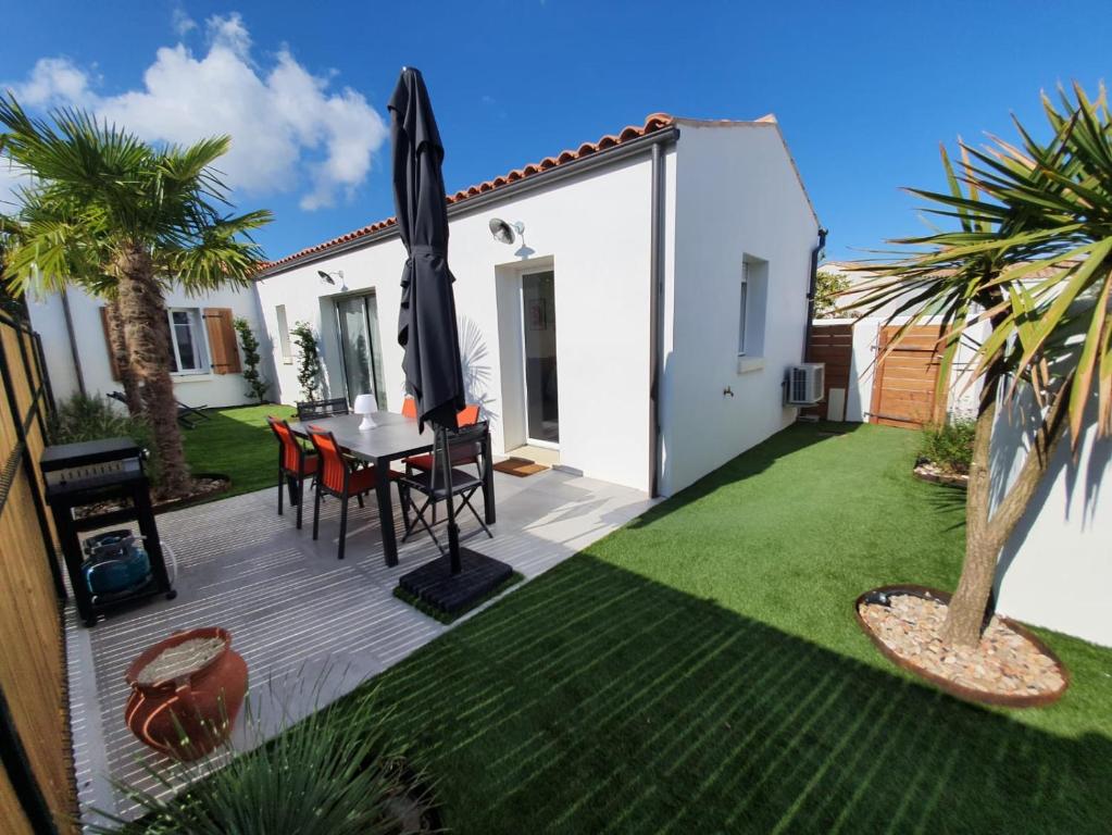 un patio con mesa y sombrilla en Le clos des baigneurs, en Dolus d'Oléron