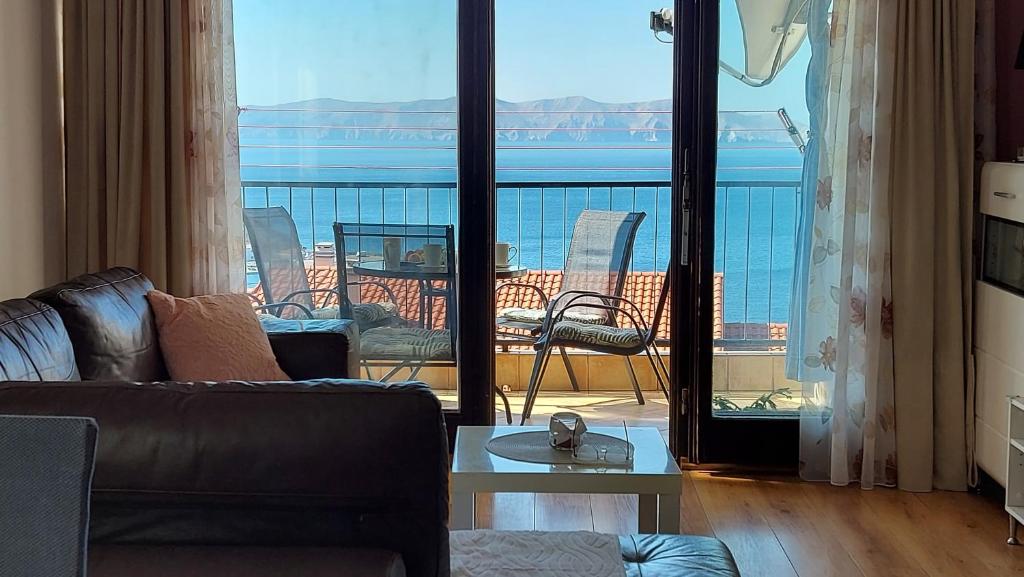 sala de estar con sofá y balcón con vistas. en Apartment Mira, en Senj