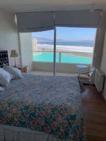 a bedroom with a bed and a view of the ocean at Departamentos Laguna del mar in La Serena