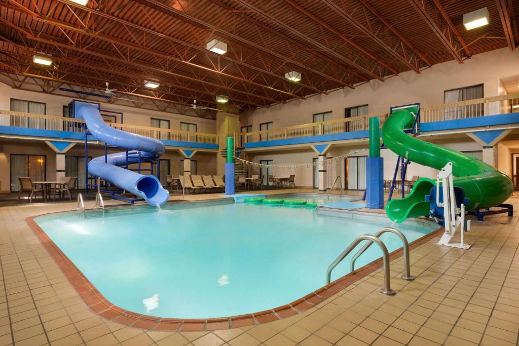a large swimming pool with a water slide in a building at Ramada by Wyndham Fargo in Fargo