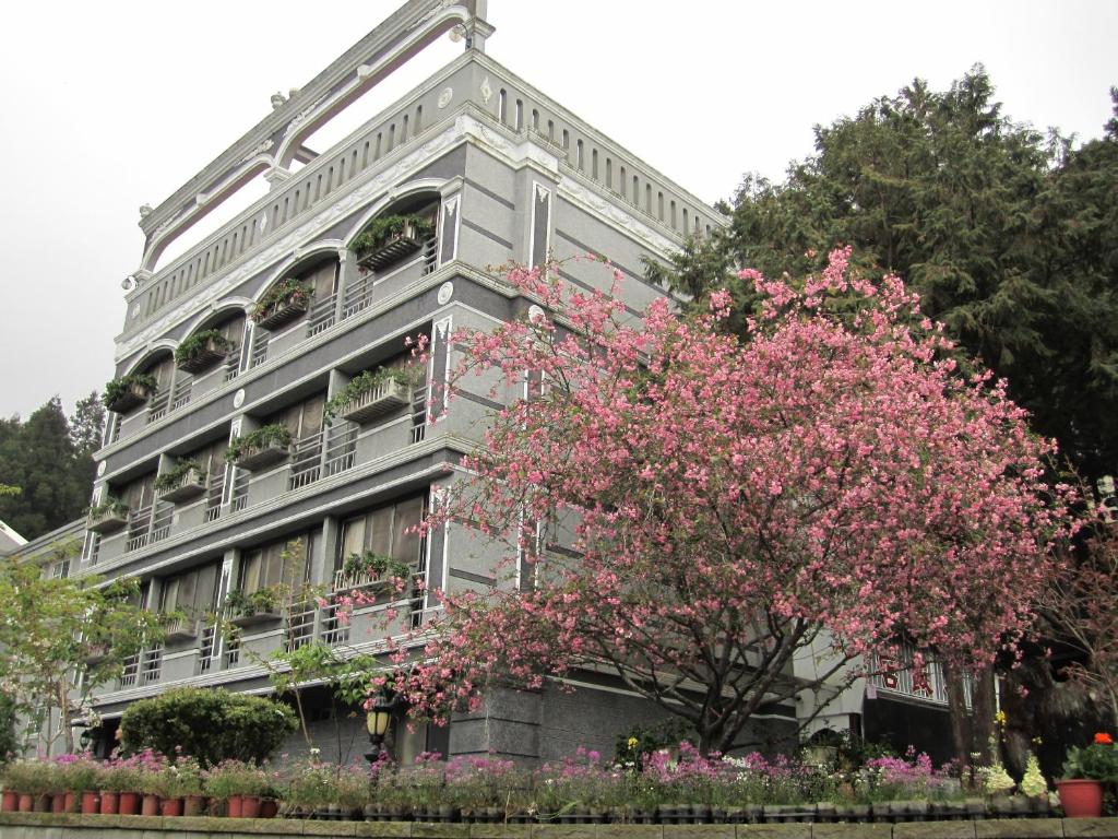 un edificio con un árbol florido delante de él en Kao Feng Hotel, en Zhongzheng