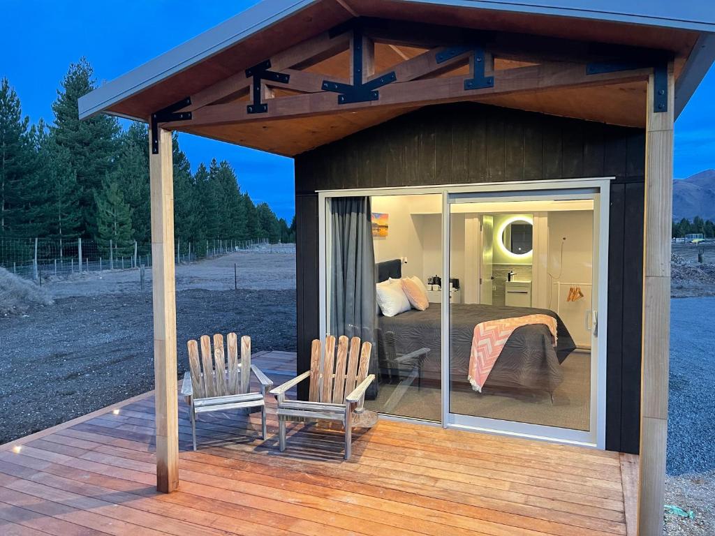 Zimmer mit einem Bett und zwei Stühlen auf einer Terrasse in der Unterkunft Clever Cube - Amazing Alpine Studio Unit in Twizel