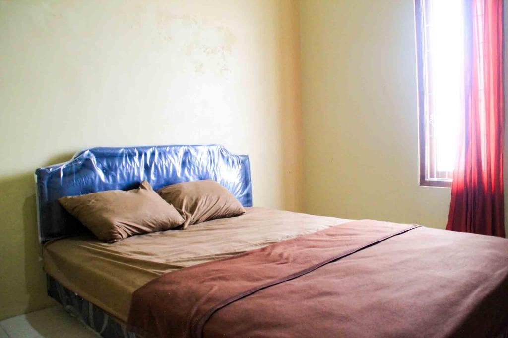 a bed with a blue headboard in a bedroom at Puri Karomah Syariah RedPartner in Lamongan
