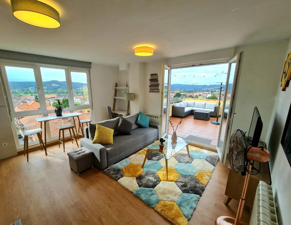 - un salon avec un canapé et une table avec vue dans l'établissement Luminoso apartamento con gran terraza, à Renedo de Piélagos
