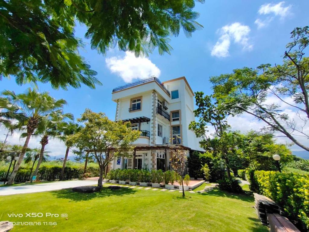 una casa blanca con árboles delante en Fish House 宜蘭獨棟別墅 戲水池 生態DIY 安農溪自行車, en Dongshan