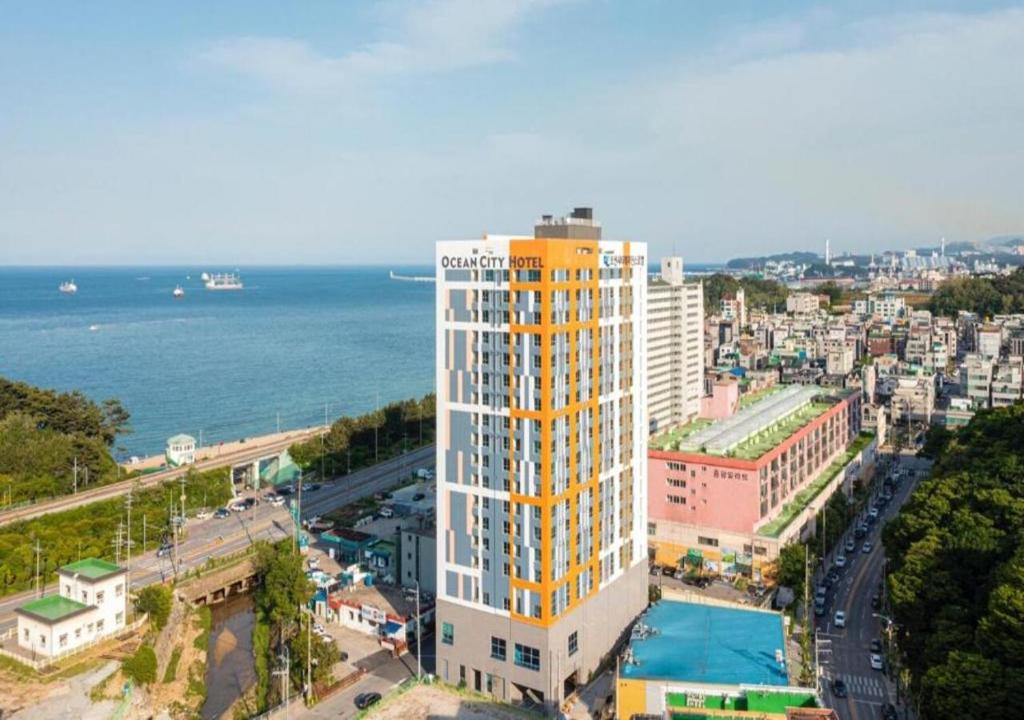 Donghae Oceancity Residence Hotel في دونغ هاي: مبنى طويل أصفر وبيض بجوار المحيط
