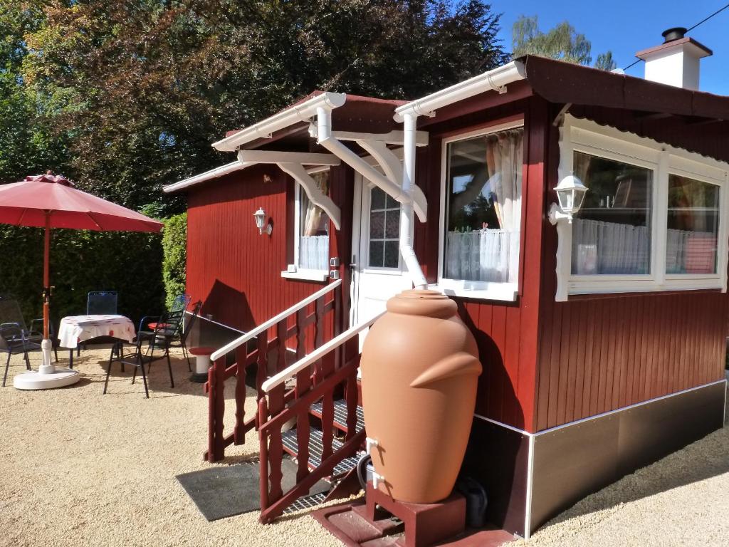 a small red house with a large vase in front of it at Ferienhaus Weiherblick in Pottum