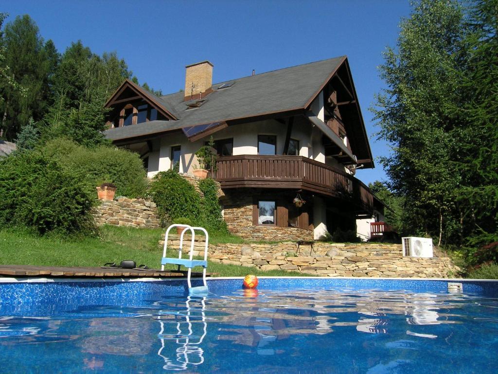 a house with a swimming pool in front of a house at Woodhouse in Rokytnice nad Jizerou