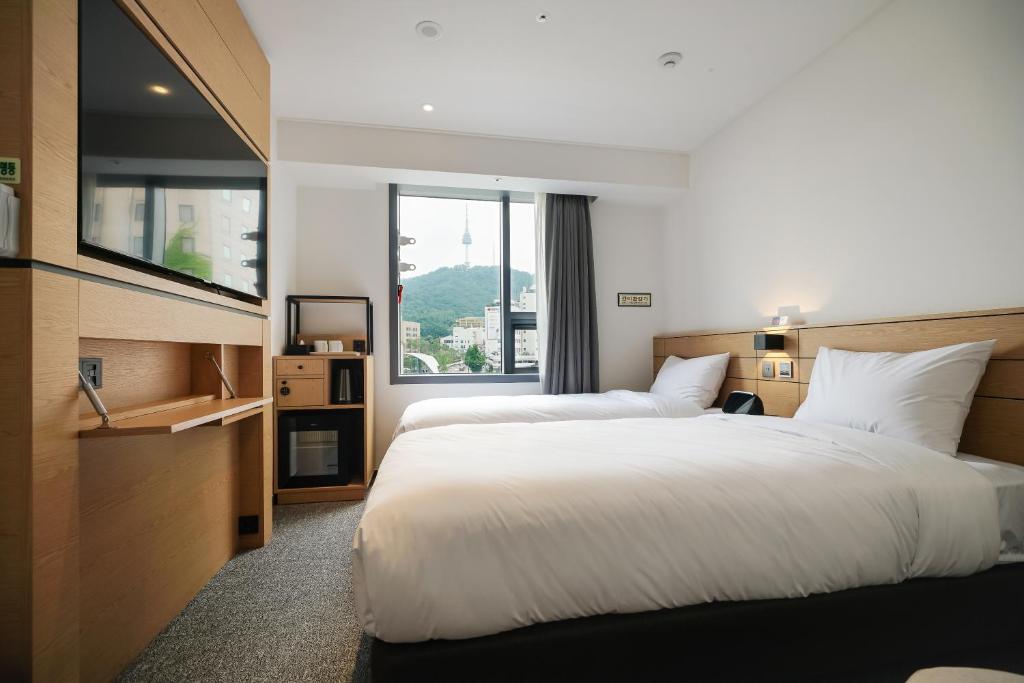 a hotel room with two beds and a window at Henn na Hotel Seoul Myeongdong in Seoul